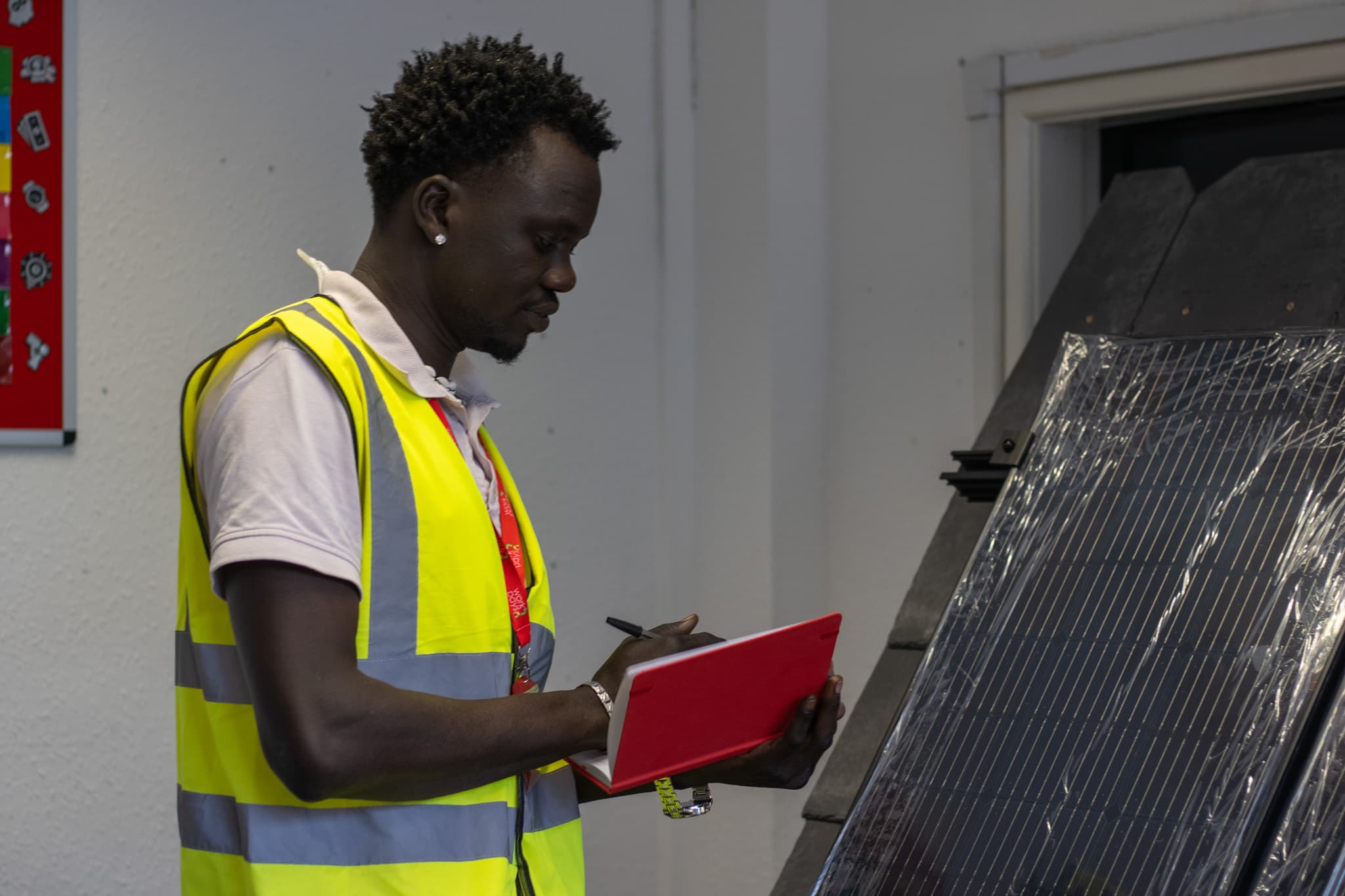 Trainee taking notes beside a solar PV panel